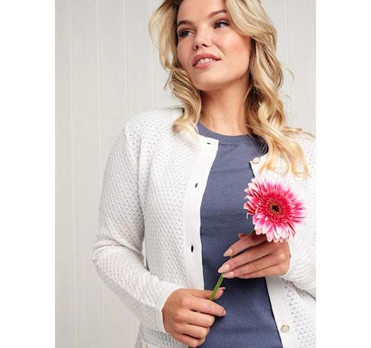 Kvinde med Skovhuus cardigan m. Guld 2880, holder en blomst.