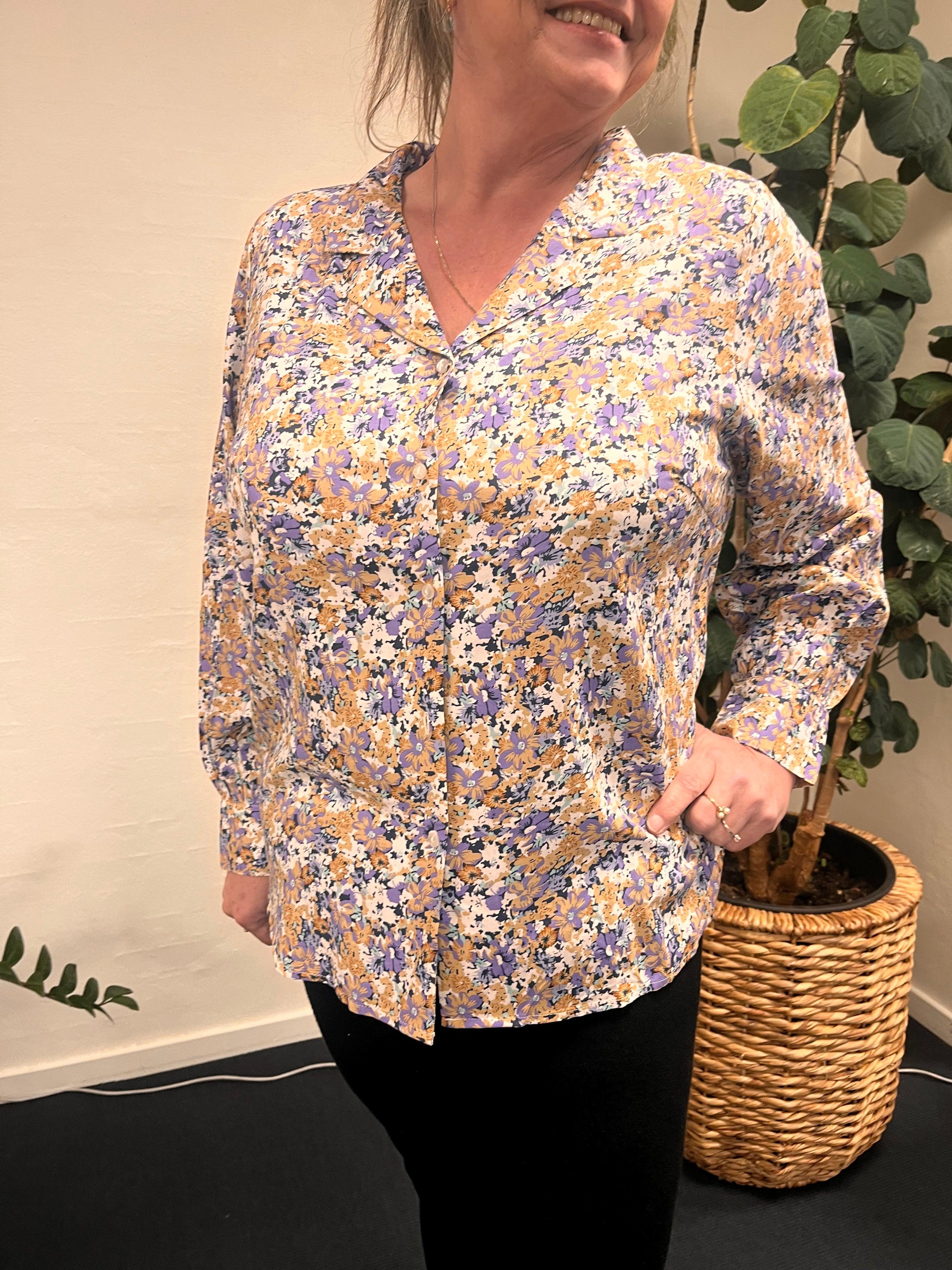 Kvinde iført Only Carmakomaesh blomster bluse foran en plante.
