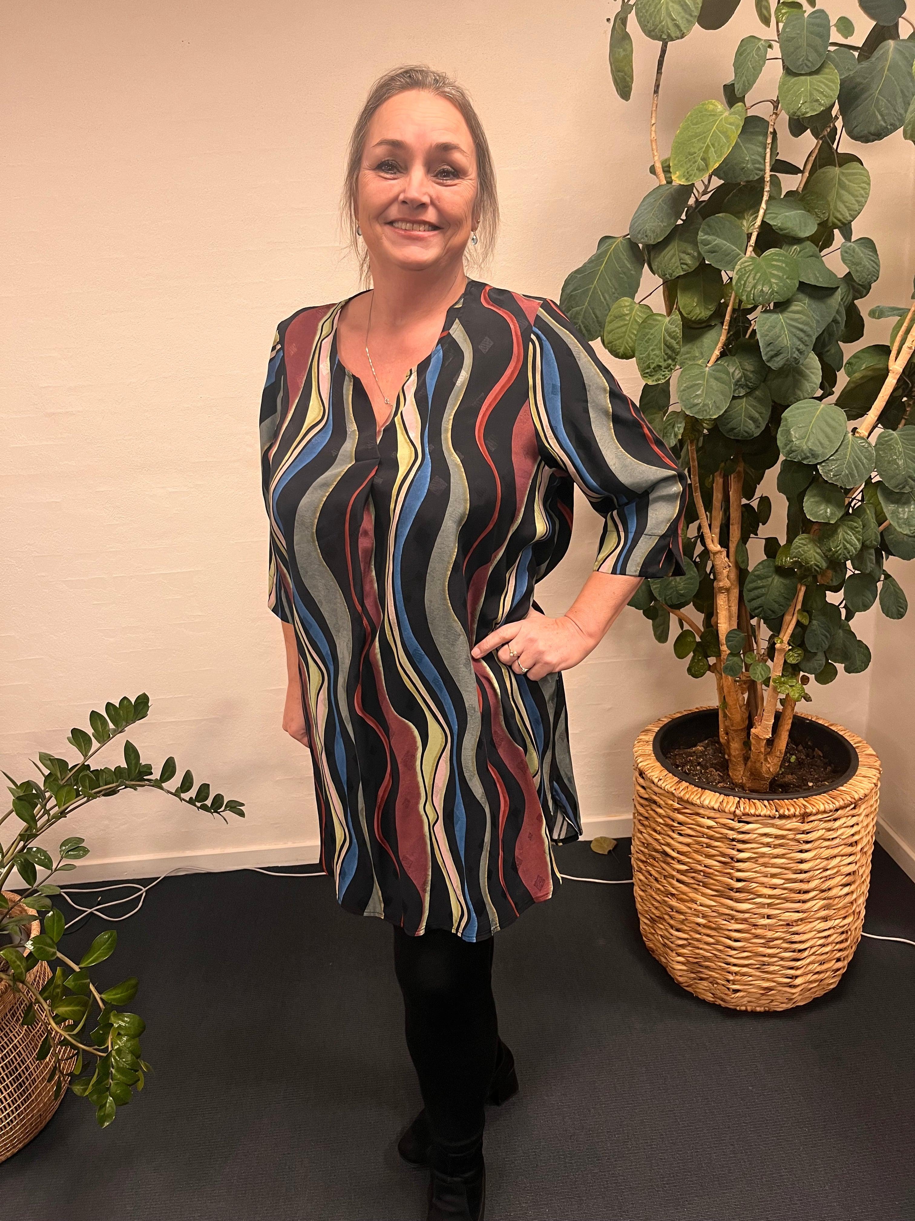 Kvinde iført Pont Neuf Brille tunika foran plante.