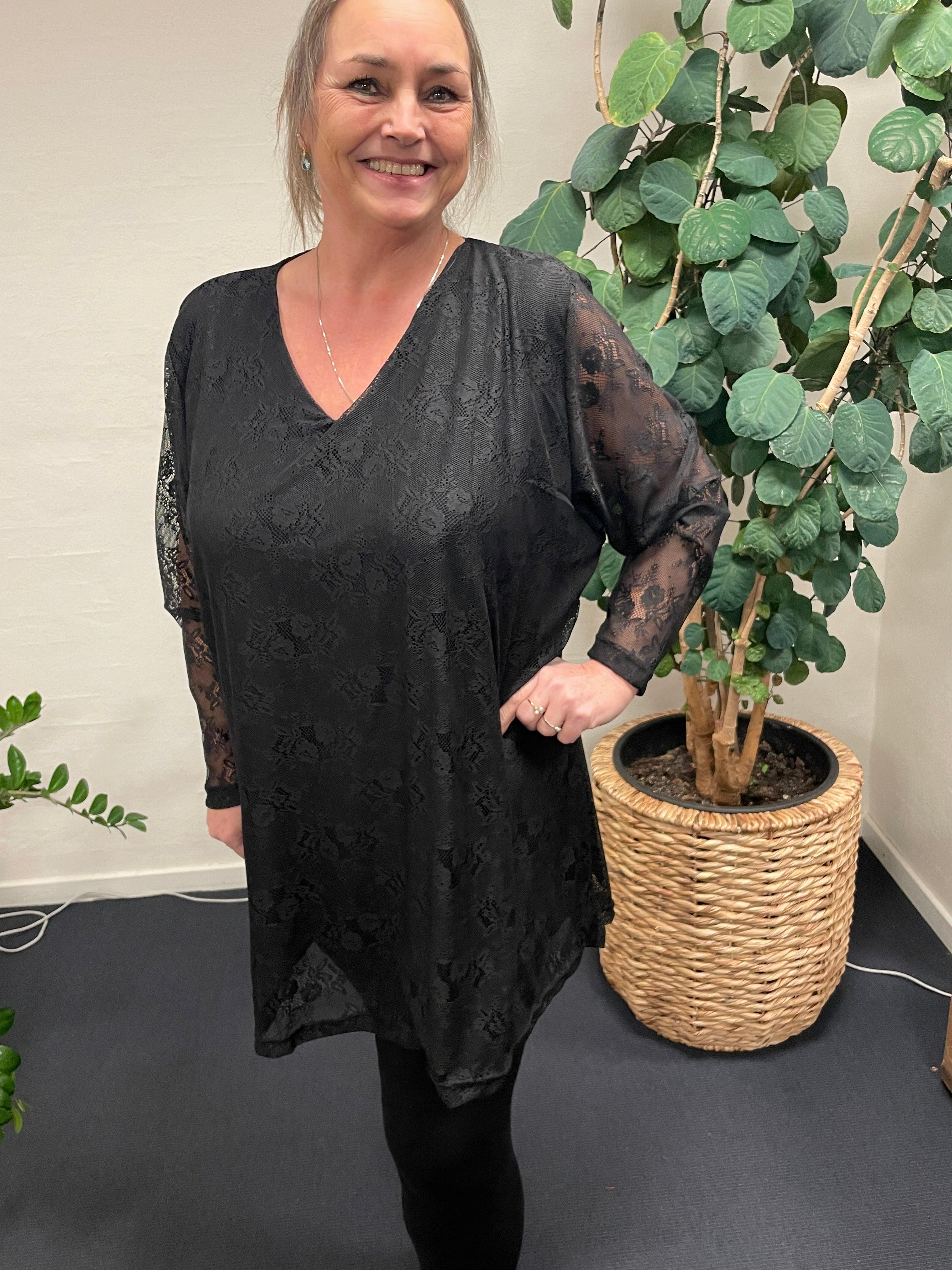 Kvinde i sort Pronto woman - LisG blondetunika foran plante.