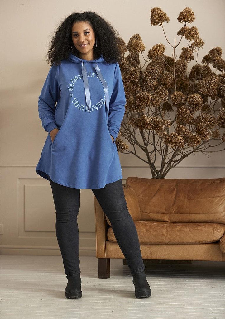 Zhenzi Twist leggings blå på kvinde foran sofa.